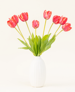 De Zijden kunstbloemen boeket Franse Tulp rood is gerangschikt in een vaas van wit keramiek, met acht rode en gele tulpen met groene bladeren tegen een effen lichte achtergrond.