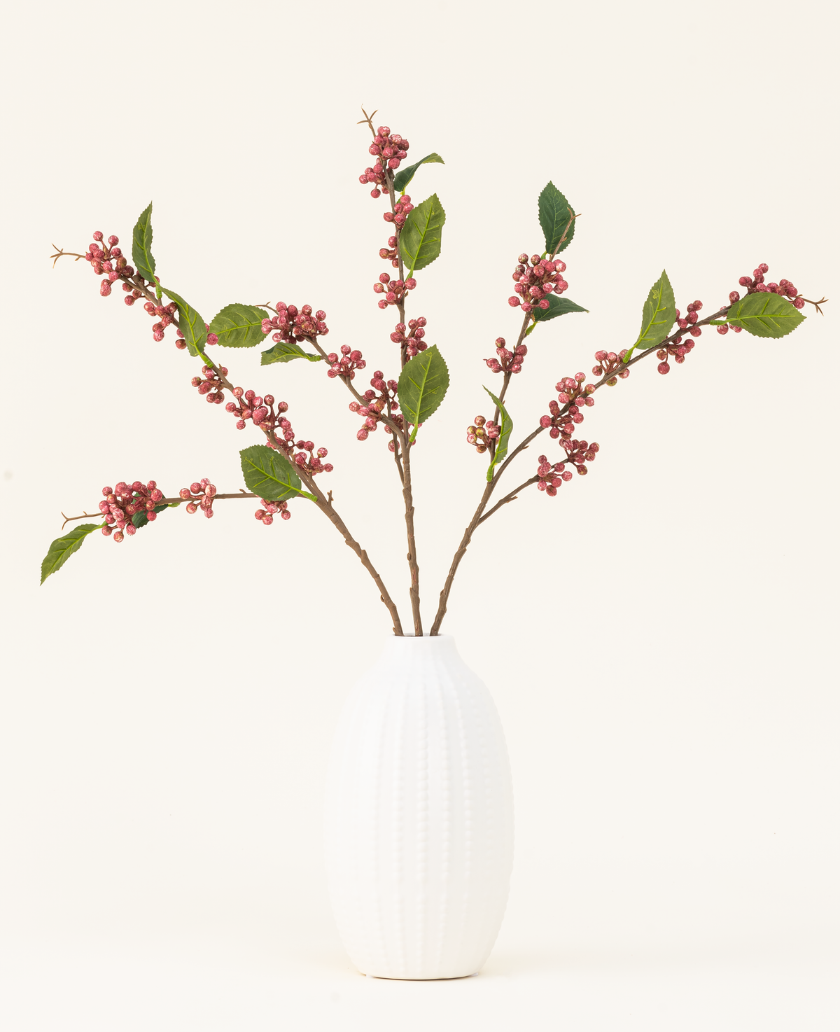 Zijden kunstbloemenboeket Berries Roze met groene bladeren in een witte vaas, perfect voor een minimalistisch interieur.
