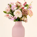 Zijden kunstbloemenboeket Boho Blossom, bestaande uit roze en witte zijden kunstbloemen, geschikt in een geribbelde, lichtroze vaas.
