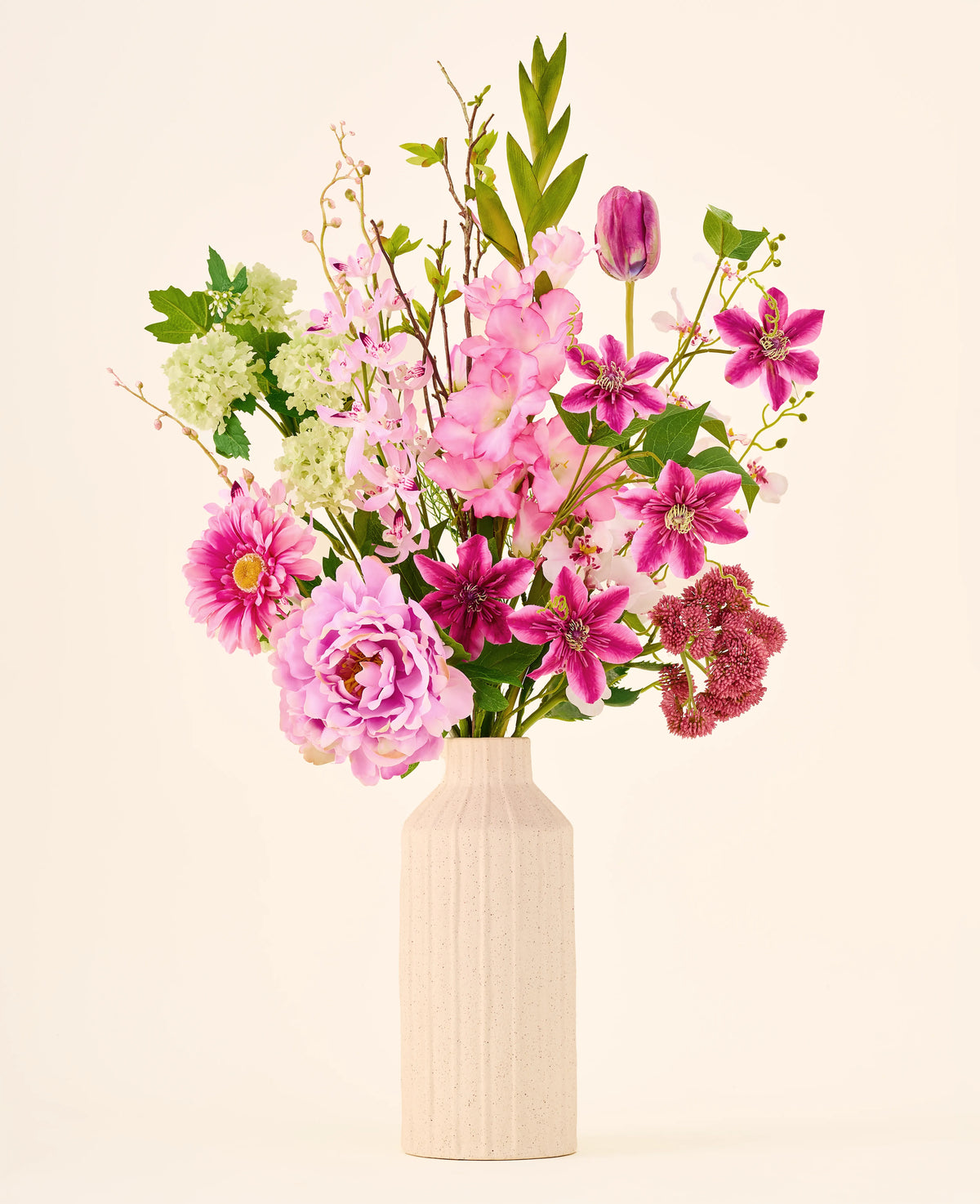 Een onderhoudsvrij boeket Pink Passion van Zijden kunstbloemen, bestaande uit roze en groene kunstbloemen in een geribbelde, gespikkelde keramische vaas.