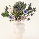 In een witte vaas met structuur staat het Zijden kunstbloemen boeket Blue Belle - met hortensia's, margrieten, roze rozen en meer - tegen een effen lichte achtergrond.