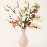 Een roze vaas van keramiek bevat het Zijden kunstbloemen boeket Springtime Poem, met witte, roze en groene bloemen met groene bladeren en bruine stelen, tegen een lichte achtergrond.