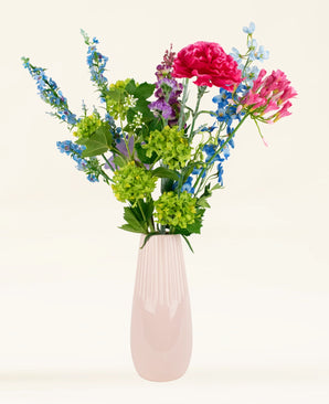 Het Zijden kunstbloemen boeket Blossom Breeze heeft roze, blauwe, groene en paarse bloemen in een roze keramische vaas - perfect om een levendig accent aan elke kamer te geven.
