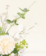 Een close-up van het Zijden kunstbloemen boeket Claire de Lune, met witte en crèmekleurige bloemen, groene bladeren en delicaat wit gebladerte op een lichte, neutrale achtergrond.