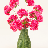 Een groene vaas met bladmotief toont het Zijden kunstbloemen boeket Kersenbloesem Roze-helderroze, pluizige zijden kersenbloesems met groene bladeren-tegen een effen lichte achtergrond.