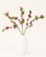 Zijden kunstbloemenboeket Berries Roze met groene bladeren in een witte vaas, perfect voor een minimalistisch interieur.