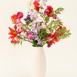 In een vaas met witte structuur staat het Zijden kunstbloemen boeket Pink Pop, met levendige kunstroze bloemen en groene bladeren tegen een lichte achtergrond.