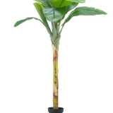 De Kunstplant Bananenboom 180 cm heeft brede groene bladeren en een gestructureerde steel in een kleine zwarte pot, tegen een effen witte achtergrond.