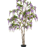 De Kunstplant Blauweregen 280 cm is een hoge kunst blauwe regen boom in een zwarte pot, met meerdere slanke bruine stammen en cascade paarse bloemen met groene bladeren, tegen een effen witte achtergrond.