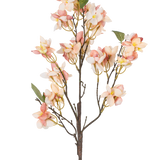 De Kunstbloem Bloesem 60 cm roze heeft een enkele kunststengel met trossen lichtroze en crème bloemen, kleine gele hartjes en groene bladeren tegen een witte achtergrond.