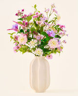 In een witte keramische vaas staat een kleurrijk boeket van roze, paarse en witte bloemen uit de collectie ‘Zijden kunstbloemen boeket Royal Bloom’, geaccentueerd met groene bladeren en gepresenteerd tegen een effen, lichte achtergrond.
