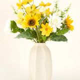 Het Zijden kunstbloemen boeket Sunny Whisper, met zonnebloemen, witte dahlia's en groene bladeren in een beige keramieken vaas, komt prachtig tot zijn recht tegen een lichte achtergrond.