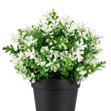 De Kunstplant Klavertje vier wit UV 22 cm is een zwarte bloempot met kunstmatige groene bladeren en kleine witte bloemen op een effen witte achtergrond.