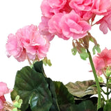 Close-up van felroze Kunst Geranium 40 cm roze bloemen met gegolfde bloemblaadjes en groene bladeren tegen een witte achtergrond, die de levensechte schoonheid van deze kunstbloeier benadrukt.