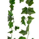 De Kunst Klimop Slinger 180 cm groen heeft hartvormige kunstmatige groene klimopbladeren op dunne, krullende stelen, hangend tegen een witte achtergrond.