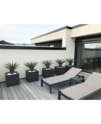 Modern terras met twee grijze loungestoelen en vijf Kunstplant Agava Pandora 85 cm UV in bijpassende vierkante plantenbakken, gerangschikt bij een wit houten hek voor een strakke, minimalistische look.