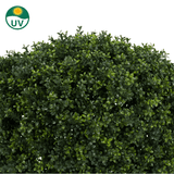 Een close-up van de Kunstplant Buxus op stam romeinse stijl UV 95cm toont dichte, glanzend groene kunstbladeren. Een UV-beschermingssymbool linksboven benadrukt de geschiktheid voor buitengebruik.