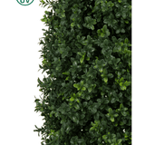 Close-up van Kunstplant Buxus Pyramide UV 120 cm toont dicht groen blad met kleine, ronde bladeren. Een cirkelvormig UV-beschermingssymbool met een gele zon linksboven benadrukt de UV-bestendigheid van de plant tegen een witte achtergrond.