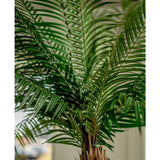 Close-up van de Kunstpalm Phoenix De Luxe 210 cm, met lange, smalle groene bladeren en een bruine stam met textuur, tegen een zacht vage achtergrond.