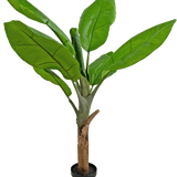 De Kunstplant Bananenboom 120 cm is een bananenplant in pot met grote, levendige groene bladeren en een dikke bruine stengel, tegen een witte achtergrond.
