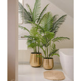 Een Kunstplant Phoenix 180 cm met weelderige groene bladeren in een glanzende gouden pot staat naast een wit bad en een beige geweven mat in een moderne, minimalistische badkamer, aangevuld met een spiegel en een raam voor een serene uitstraling.