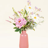 Een roze vaas toont het Zijden kunstbloemen boeket Misty Minthe, met witte margrieten, roze pioenrozen, paarse bloesems en eucalyptustakjes, tegen een lichte neutrale achtergrond.