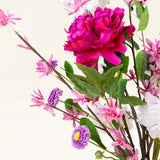 Het Zijden kunstbloemen boeket Pink Reverie heeft een grote magenta pioenroos, kleine roze bloemen, paarse madeliefachtige bloemen en groene bladeren in een vaas-een romantisch boeket tegen een lichte achtergrond.