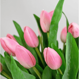 Een close-up van het Zijden kunstboeket Tulpen in vaas Roze toont roze tulpen met groene bladeren tegen een lichte, neutrale achtergrond.