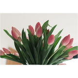 Het Zijden kunstboeket Tulpen in vaas Roze toont roze tulpen met groene bladeren, tegen een lichte achtergrond en van onderaf gezien.