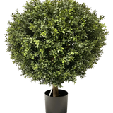 De Kunst Buxus op stam UV d60 cm is een dichte, ronde kunst vormsnoei met kleine groene blaadjes en een zichtbare enkele stam, netjes getrimd tot een bol en geplaatst in een eenvoudige zwarte pot.