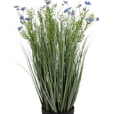 De Kunstgras paarse Gesang Bloem uiengraspot (90cm, brandvertragend) heeft hoog, dun groen kunstgras en delicate lichtpaarse bloemen in een zwarte pot, tegen een witte achtergrond.