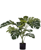 De Kunstplant Monstera 85 cm is een kunstplant in pot met grote, glanzend groene bladeren met natuurlijke splijten en gaten, tegen een witte achtergrond.