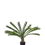 De Kunstplant Cycus Palm Deluxe 95 cm heeft overhangende, vederachtige groene bladeren en een dikke, gestructureerde stam tegen een effen witte achtergrond.