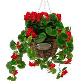 De Kunstbegonia Rood in Mand UV 70cm heeft levendige rode kunstbegonia's en weelderige groene bladeren in een gevlochten mand met slingerende stelen, hangend aan een metalen ketting en afgewerkt met een kleine ovale plaquette met de tekst "Flowers.
