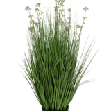 De Kunstgras Prei Bloem Ui Graspot 100cm brandvertragend heeft een zwarte pot met hoge, dunne groene kunstbladeren en kleine paarse bloemen op lange stelen, tegen een witte achtergrond.