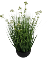 De Kunstgras Prei Bloem Ui Graspot 60cm brandvertragend is een kunstplant in pot met lange groene bladeren en kleine witte bloemtrosjes in een ronde zwarte pot, afgebeeld tegen een witte achtergrond.